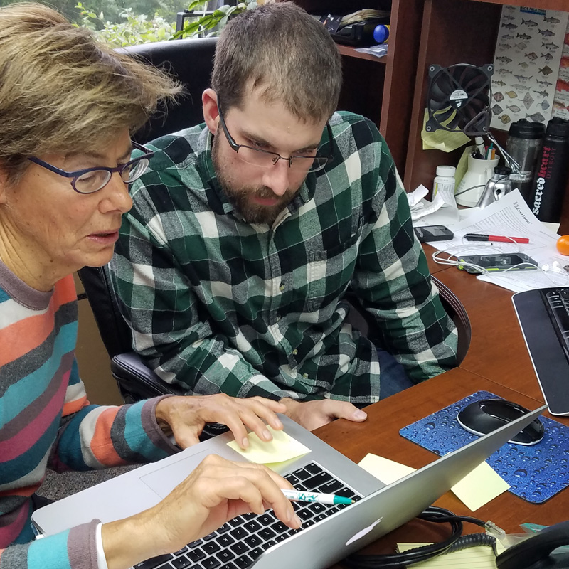 Photo of Saltwater Inc. office with two EM colleagues at a computer in Anchorage Alaska.